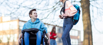 Jongen in rolstoel praat met meisje